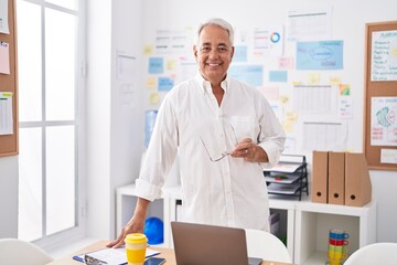 Middle age grey-haired man business worker smiling confident standing by desk at office