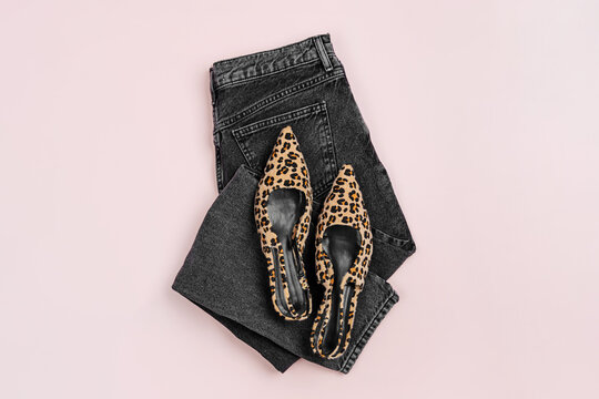 Leopard print shoes and black jeans on  pink background. Fashion spring, summer or autumn outfit. Women's stylish and elegant clothes with accessory.  Flat lay, top view, overhead.