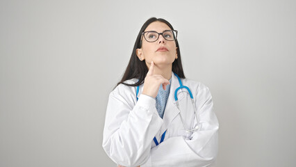 Young hispanic woman doctor standing with doubt expression thinking over isolated white background