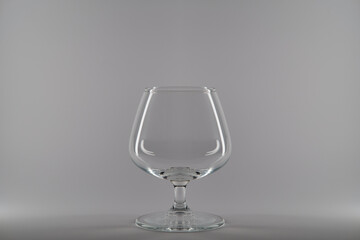 Empty clean cognac glass isolated on white gray background.