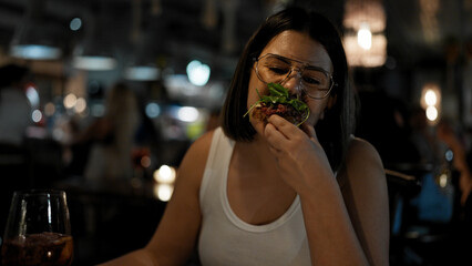 Young beautiful hispanic woman eating delicious italian food at the restaurant