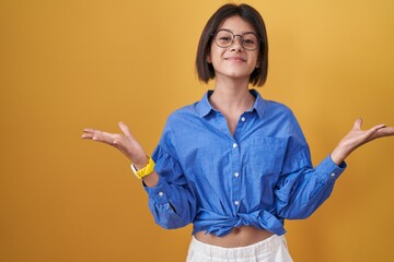 Young girl standing over yellow background celebrating crazy and amazed for success with arms...