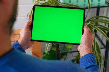 Close up Mans hands Holding Tablet Computer with Green Screen Mock Up Display. Relaxing at Home