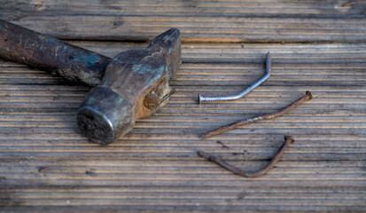 Old rusty nails and hammer on wooden background