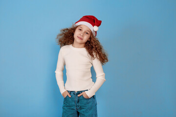 Little smiling afro-american girl with Santa hat on blue background.