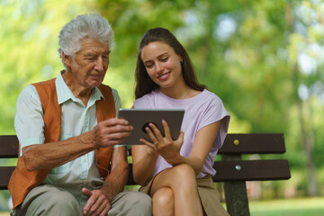 Caregiver helping senior man to shop online on tablet. The risk of online shopping scams targeting...