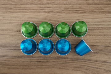 Espresso coffee capsules blue and green in wood background.