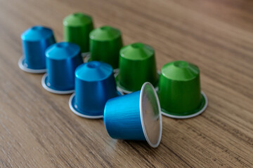 Espresso coffee capsules blue and green in wood background.