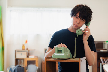 固定電話で電話をする若い男性