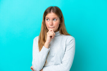 Young blonde woman isolated on blue background having doubts and thinking