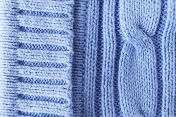 Texture, background, pattern. The woolen fabric is knitted with knitting needles in pastel shades of blue.