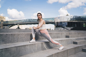 Fitness enthusiast stretches on city stairs, bridge and modern building in backdrop, poised for...
