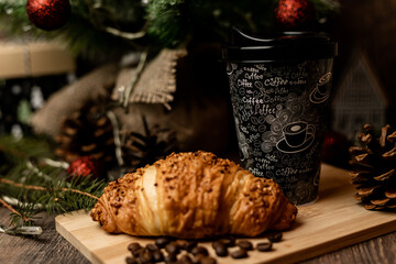 Coffee to go and croissant near the Christmas tree. New Year's Eve Sweets