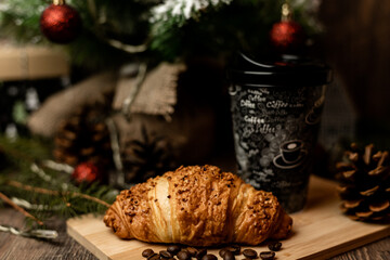 Coffee to go and croissant near the Christmas tree. New Year's Eve Sweets
