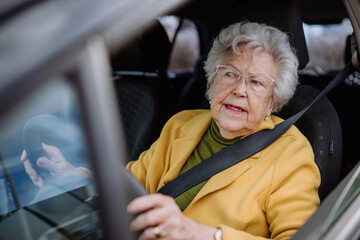 Focused senior woman driving car alone, enjoying car ride. Safe driving for elderly adults, older driver safety.