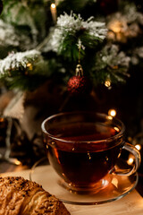 Cup of tea with croissant near Christmas tree.New Year's Eve at home with family