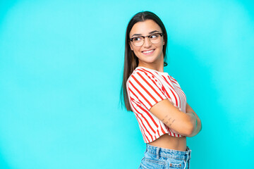 Fototapeta na wymiar Young caucasian woman isolated on blue background looking to the side and smiling