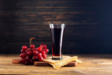 red grape juice in a glass placed on a wooden table or red wine, a delicious natural fruit juice...