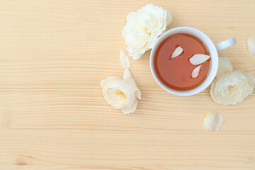 Rose petals tea with white rose in a white tea cup on the saucer top view with a copy space. On wooden table. Herbal hot drink alternative medicine concept.