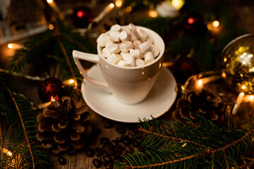 Marshmelon in a white cup on a table with Christmas lights. Christmas tree