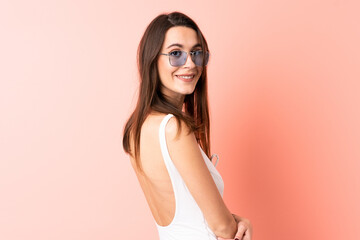 Young woman over isolated pink background in swimsuit in summer holidays