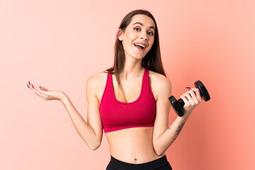 Young sport woman making weightlifting over isolated pink background with shocked facial expression