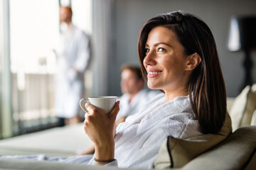 Happy young woman drinking a cup of coffee, tea in an autumn morning at wellness spa hotel