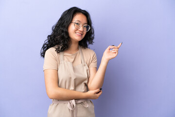 Restaurant asian waiter isolated on purple background pointing finger to the side