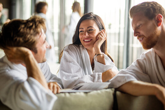 Group of happy people enjoying wellness relax weekend. Woman with two handsome men in bedroom.