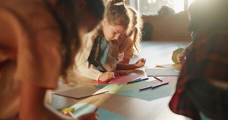 A group of preschool children draw on multi-colored sheets of paper using multi-colored pencils in a sunny room in a group at a children's school preparation club - Powered by Adobe