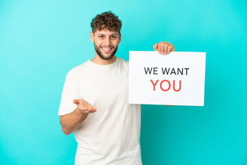 Young handsome caucasian man isolated on blue background holding We Want You board making a deal - obrazy, fototapety, plakaty