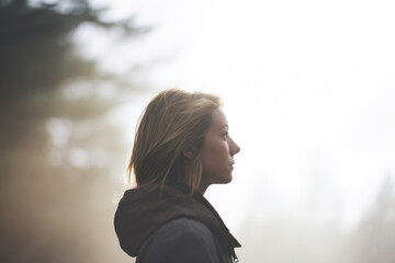 outdoor side profile portrait of a woman in misty nature with muted colors background for copy space