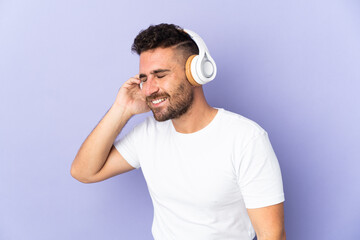 Fototapeta premium Caucasian man isolated on purple background listening music and singing