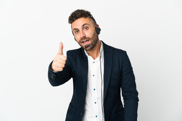 Telemarketer man working with a headset isolated on white background with thumbs up because something good has happened