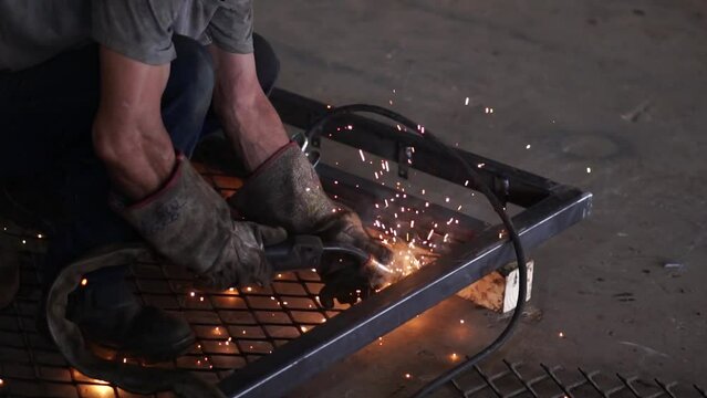 Homem com luva soldando um grade de metal