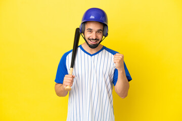 Young caucasian man playing baseball isolated on yellow background celebrating a victory in winner position