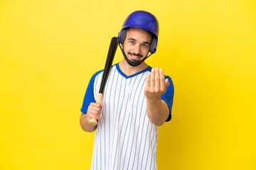 Fototapeta premium Young caucasian man playing baseball isolated on yellow background inviting to come with hand. Happy that you came
