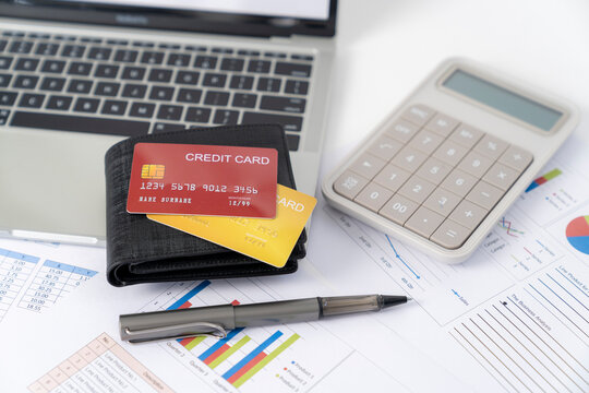 Credit card on desk with calculator, Calculating monthly expenses.