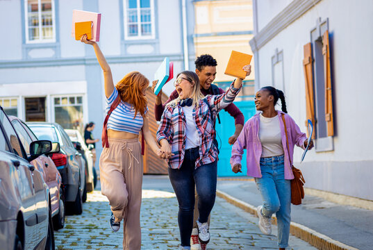 Excited group of students is walking down the street, overjoyed at the end of their studies.