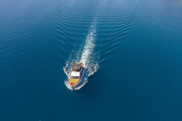 View from a height of a white speedboat sailing in the birch sea. The motor boat leaves a mark on...