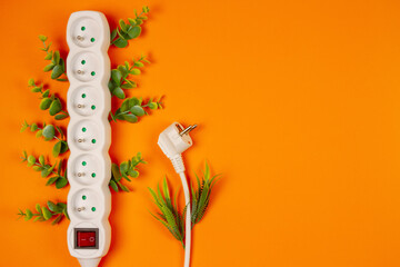 White power strip and green leaves on orange background with copy space.