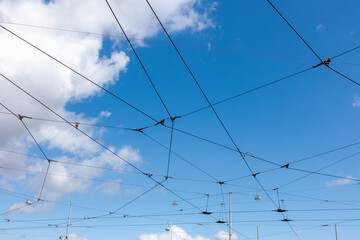 Selective focus of busy cable lines under blue sky, The connecting of the tram and Pantograph, Electric railway train and power supply lines, Cables connections and metal pole overhead catenary wire.