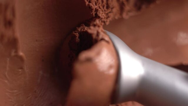 Delicious chocolate ice cream being scooped with a scoop, close-up