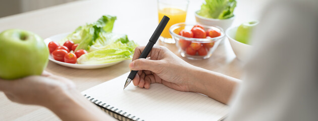 Wellbeing of health with good food control concept. Woman writing the meal note and plan to eat during diet program to loss weight goal for balance nutrition and calories. - obrazy, fototapety, plakaty