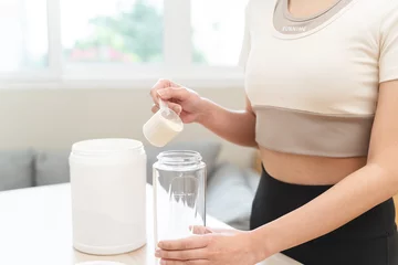 Fotobehang Diet meal replacement for weight loss, asian young woman in sportswear, hand in holding scoop making protein into bottle © Pormezz