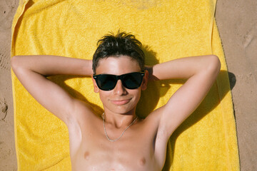 Teenage boy lying on the towel on a fabulous day at the beach.