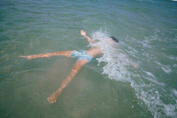 Fototapeta na wymiar Teenage girl enjoying a fabulous day at the beach. She bathes in the sea.