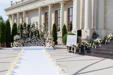 Wedding ceremony outdoor. A beautiful and stylish wedding arch, decorated by various fresh white and pink flowers, standing in the garden. Celebration day.