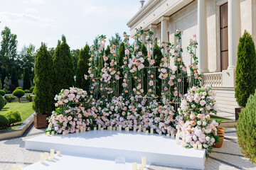 Wedding ceremony outdoor. A beautiful and stylish wedding arch, decorated by various fresh white and pink flowers, standing in the garden. Celebration day.