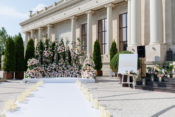 Wedding ceremony outdoor. A beautiful and stylish wedding arch, decorated by various fresh white and pink flowers, standing in the garden. Celebration day.